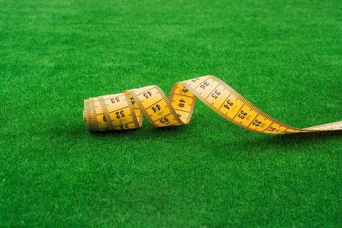 Yellow color measuring tape on green grass