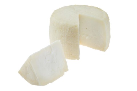 Small head of goat cheese with one section isolated on white background