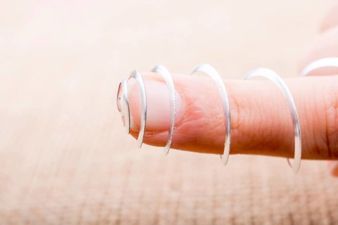 Steel spiral spring in a finger on a textured background