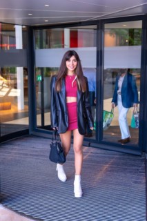 Portrait of a Caucasian girl in a red dress walking out of the revolving door of the shopping center