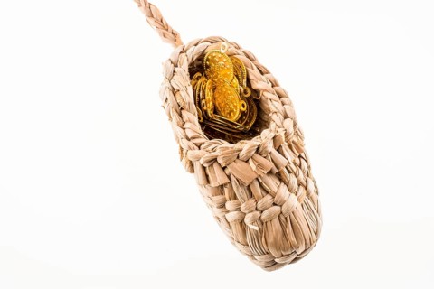 Fake gold coins in straw shoe on green grass