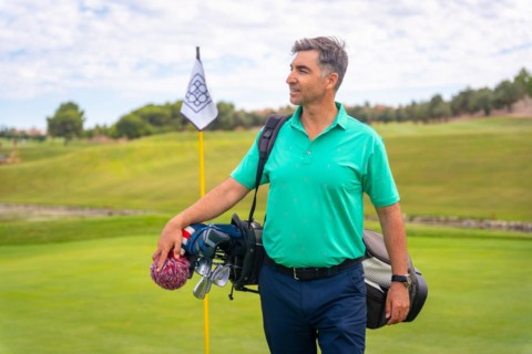 A professional Caucasian golf player on a golf course next to the flag on the green