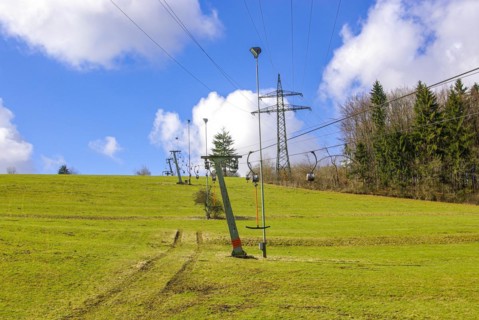 Ski lift at standstill due to lack of snow caused by climate change at the end of winter on a hill in Muensingen