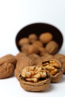 Walnuts in a brown bowl isolated on a white background