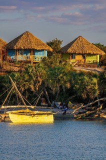 Beach bungalows above anchored sailing boats