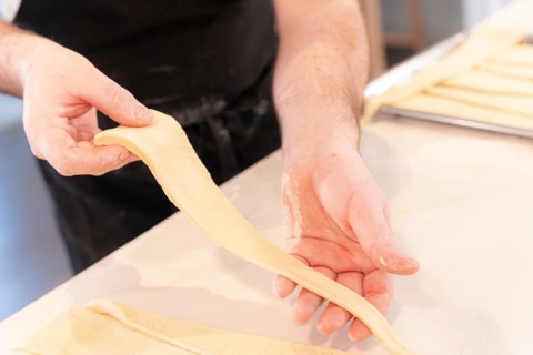 Detail of the hands of a man baking croissants collecting the triangular cuts of the puff pastry