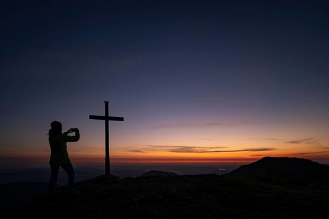 Mountaineer with mobile phone and sunrise in the background