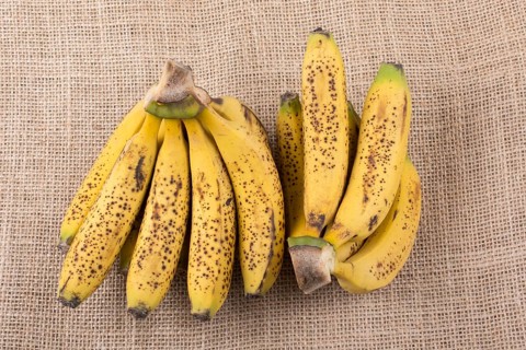 Bunch of yellow freckled bananas on a canvas texture