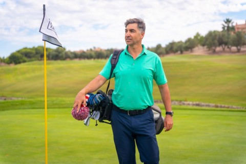A professional golf player on a golf course next to the flag on the green