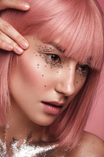 Beautiful woman in a pink wig and creative makeup with rhinestones. Beauty face. Photo taken in the studio