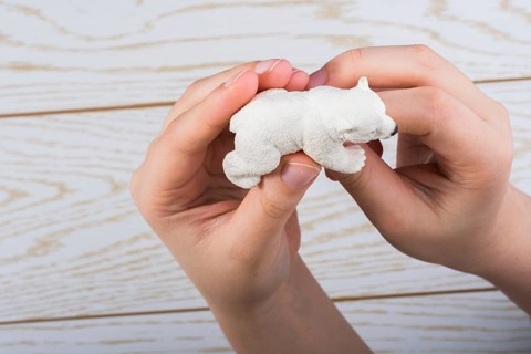Hand holding a Polar bear model on a wooden background