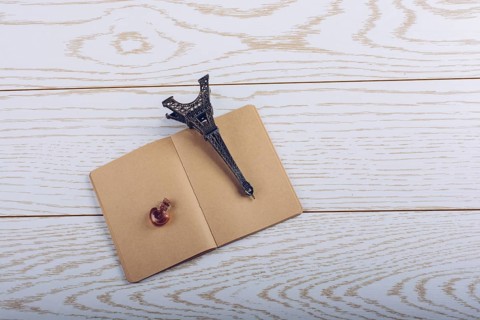 Eiffel tower miniature and a potion bottle on a brown notebook on a wooden background