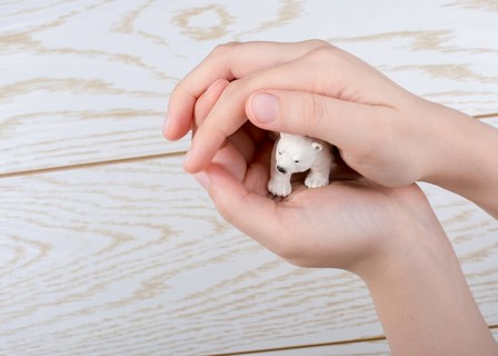 Hand holding a Polar bear model on a wooden background
