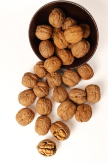 Walnuts in a brown bowl isolated on a white background