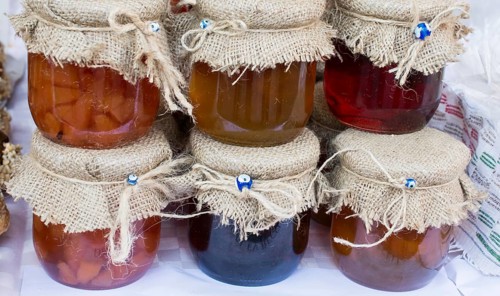 Various colored honey jars with fabric on lid in display