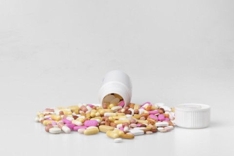 Coloured pills and capsules trickle out of plastic