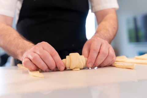 Hands of a man baking small croissants at home