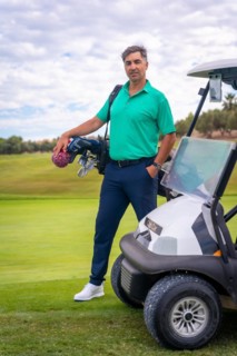 A professional golf player in a green polo shirt with the bag of clubs