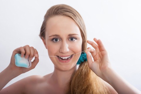 Portrait of a young woman with dental floss in her hands
