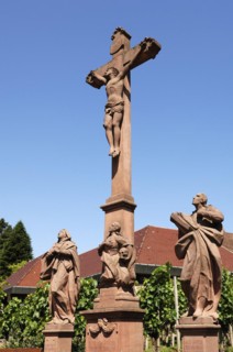 Christ cross with sculptures of saints against blue sky