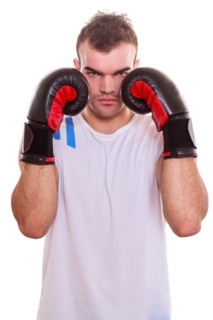 Aggressive determined young male boxer protecting his face with his fists in boxing gloves on his hat on both sides