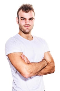 Unshaven confident handsome macho man looking at camera with folded arms and serious expression in casual t-shirt