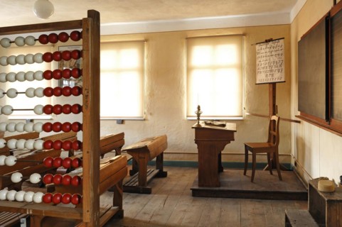Classroom with teachers desk and ABC board on the left a calculating machine