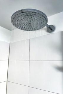 Running water from in shower with large shower head type rain shower with high water consumption