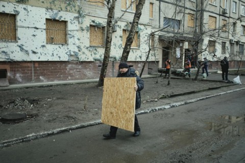 A man brings a chipboard to seal the destroyed windows