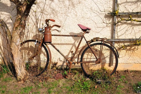 Old bicycle with milk can leaning against a house wall