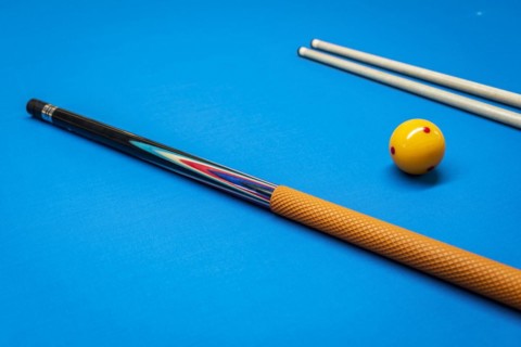 Cue sticks and a yellow ball on a billiard table