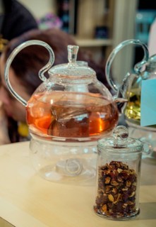 Herbal tea brewed in glass teapot and tea plant in a bottle