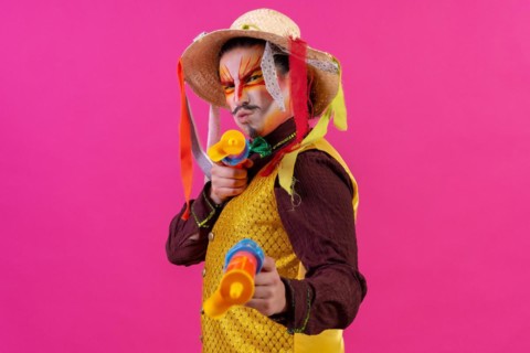 Clown with white facial makeup on a pink background