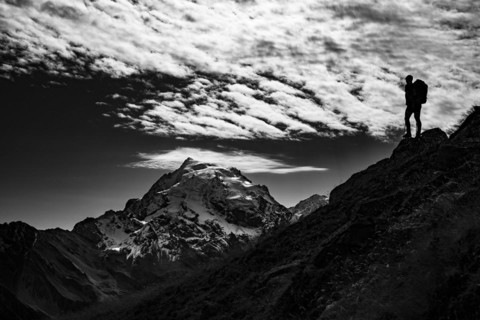Mountaineer in backlight with cloudy sky in front of Ortler summit massif