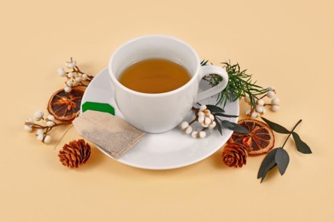 Tea cup surrounded by seasonal forest decoration on beige background