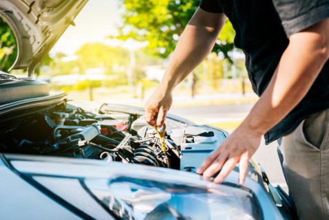 Driver hand inspecting car oil level
