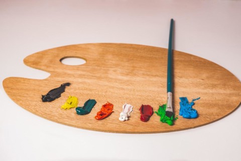 Wooden palette with colored oil paints and brushes isolated on a white background