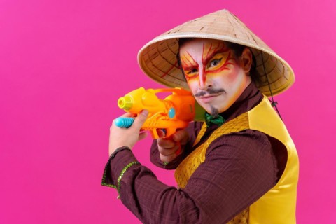 Clown with white facial makeup on a pink background