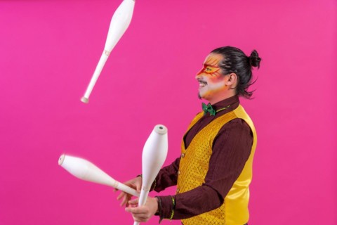 Clown with white facial makeup on a pink background