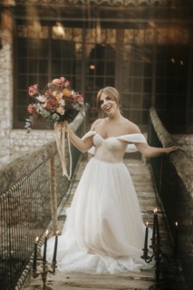 Beautiful rustic bride posing on wooden bridge full of candles