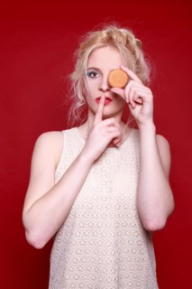 Woman holds a biscuit in front of her eye