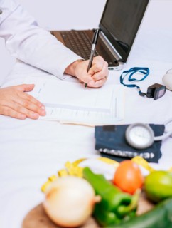 Hands of male nutritionist taking notes at his desk