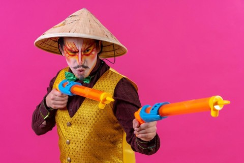 Clown with white facial makeup on a pink background