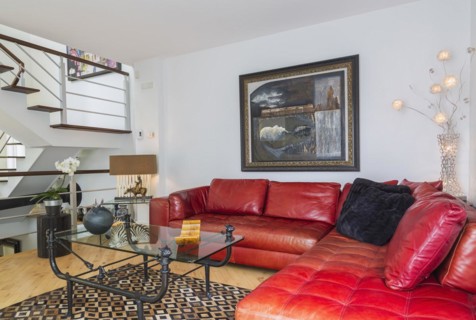 Red leather sectional sofa and black wrought iron with glass top coffee table in living room inside modern home