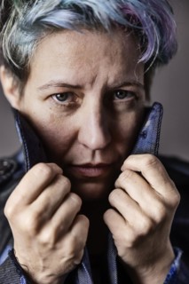 Androgynous woman with dyed hair pulls up the collar of her denim jacket