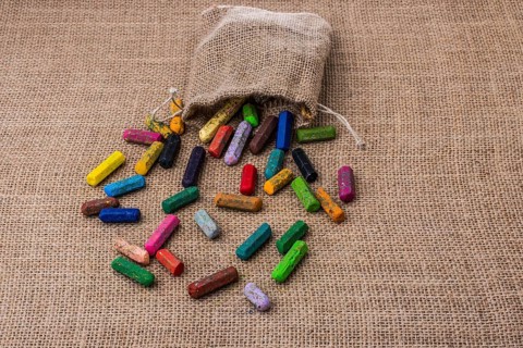 Crayons of various color out of a sack on a canvas