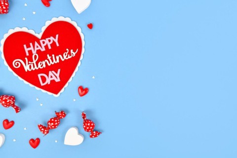 Valentines Day flat lay with heart with text Happy Valentines Day and heart ornaments on blue background with copy space