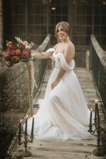 Beautiful rustic bride posing on wooden bridge full of candles