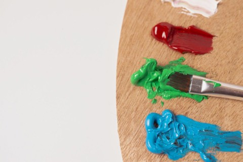 Wooden palette with colored oil paints and brushes isolated on a white background