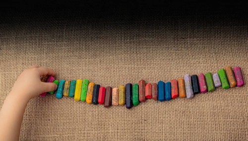 Toddlers hand putting crayons in line on canvas